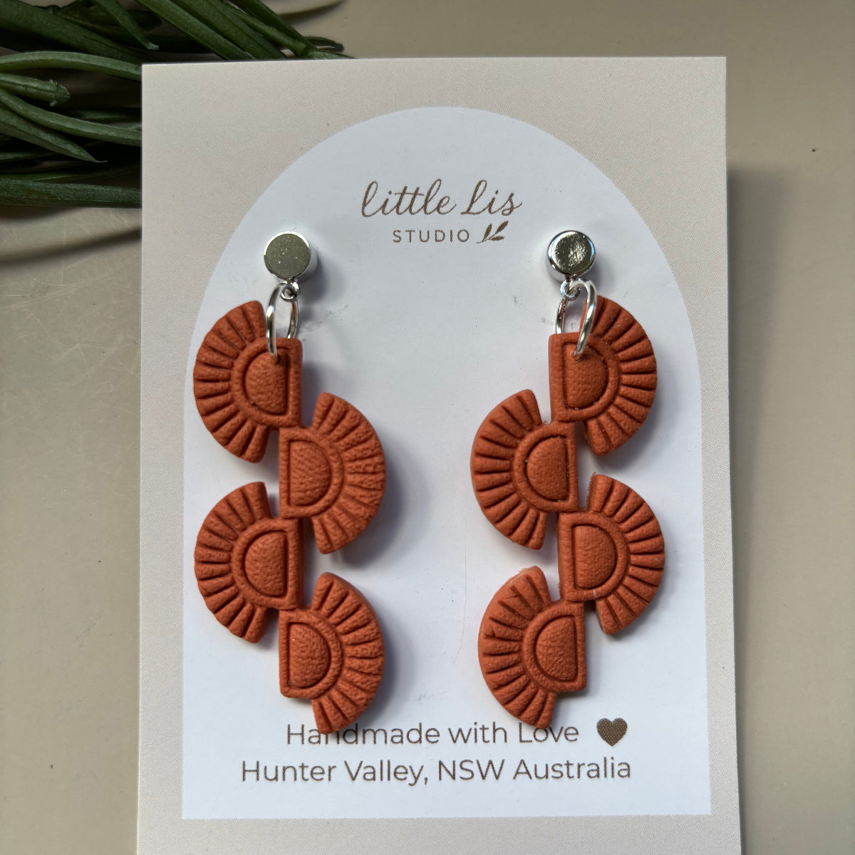 A pair of Burnt Terracotta orange textured drop earrings with silver studs, displayed on a white card labeled 'little Lis STUDIO'.