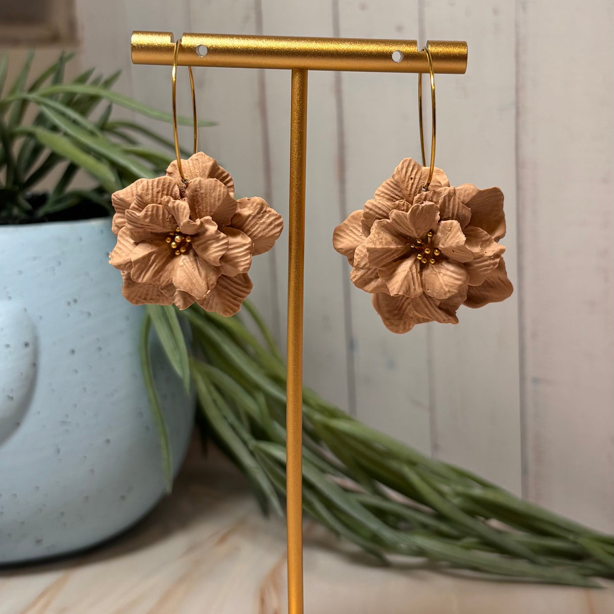 A pair of handmade flower drop earrings by Little Lis Studio, featuring layered Natural Tan Polymer Clay flowers with small gold bead centers and gold-tone wire hoops, displayed on a branded cream card.