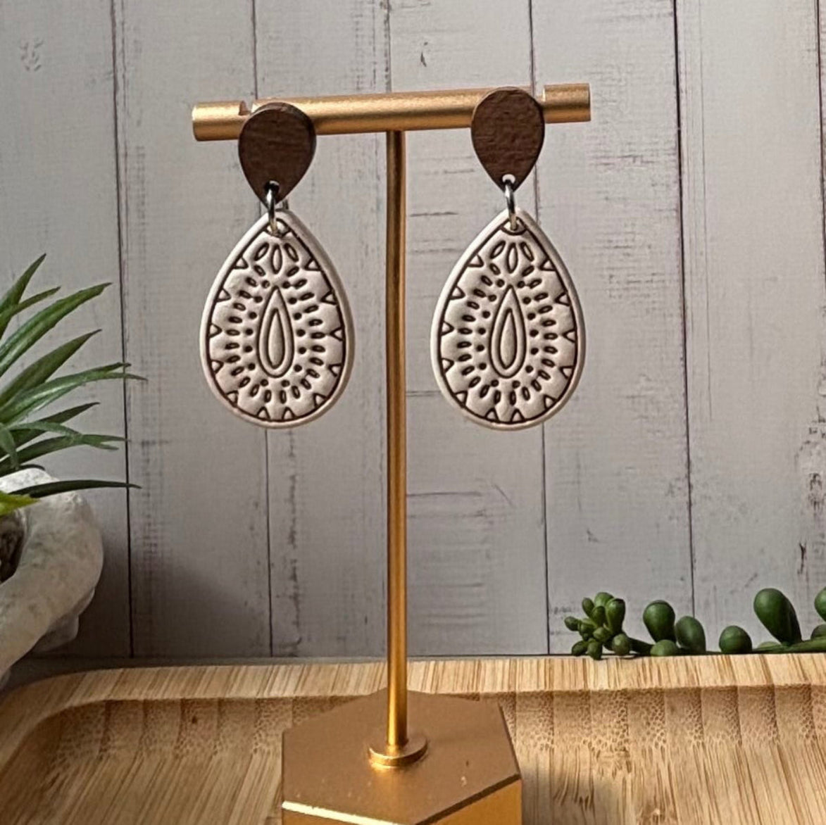 A pair of polymer clay teardrop dangle earrings with intricate brown inlay patterns and dark brown wooden studs, by littlelisstudio.com