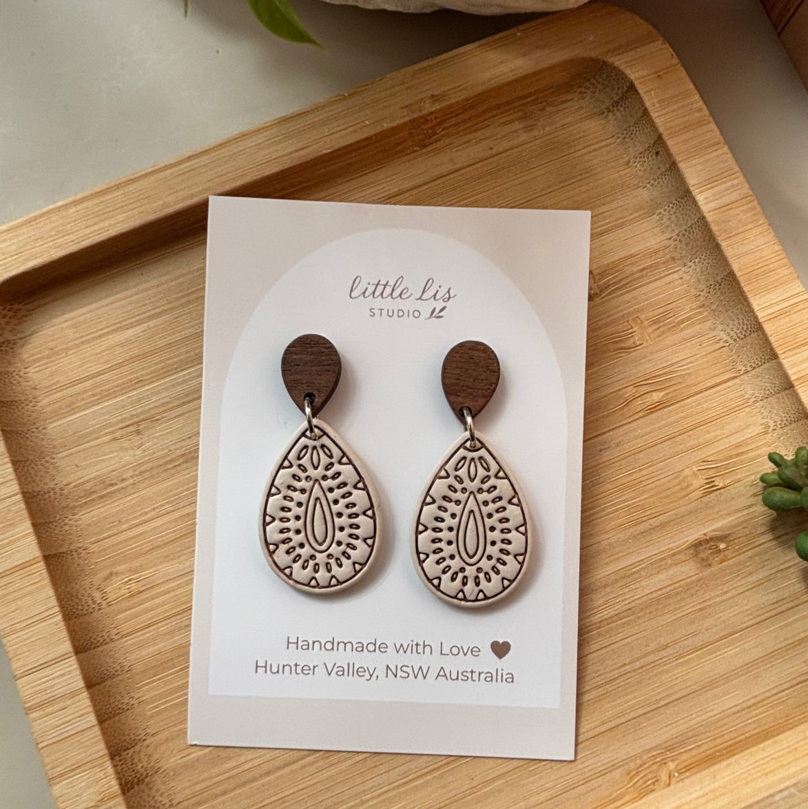 Teardrop-shaped polymer clay dangle earrings in ivory with intricate brown inlay patterns in a light wood tone, by Little Lis Studio