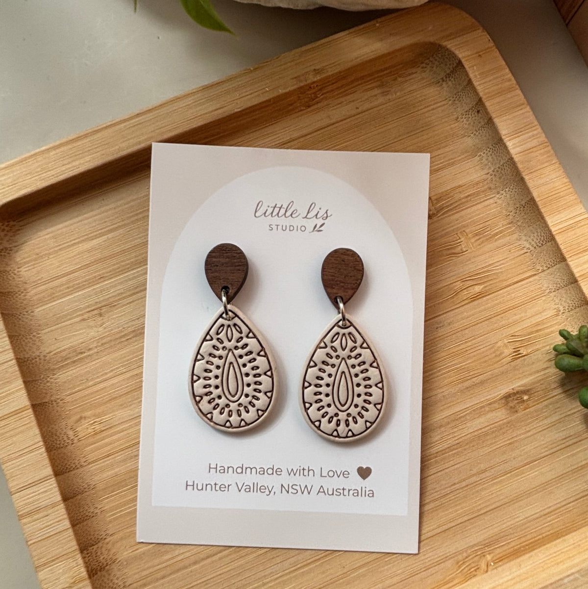 Teardrop-shaped polymer clay dangle earrings in ivory with intricate brown inlay patterns in a light wood tone, by Little Lis Studio