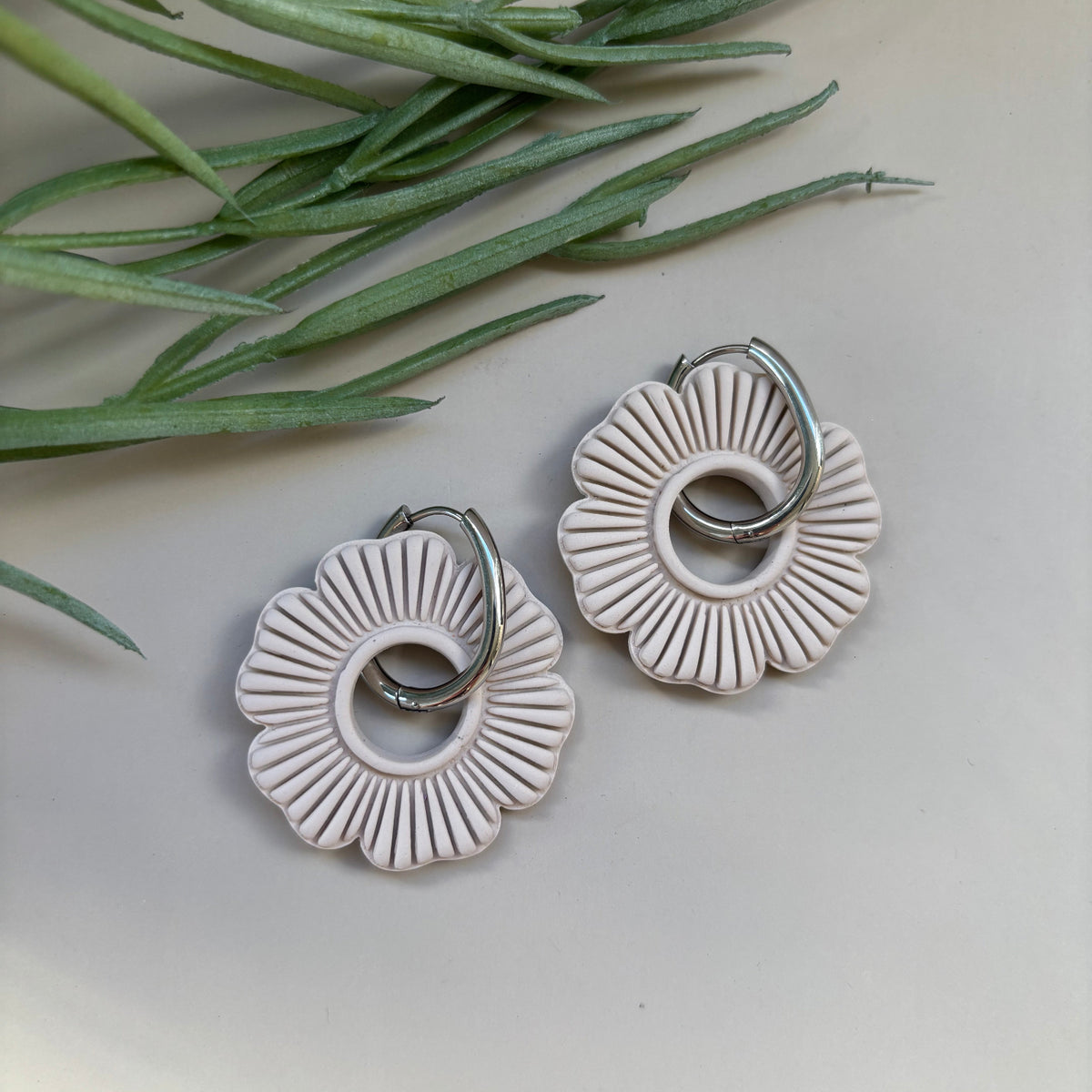Pair of ivory circular flower shaped earrings on a 18mm silver oval surgical steel hoop 
